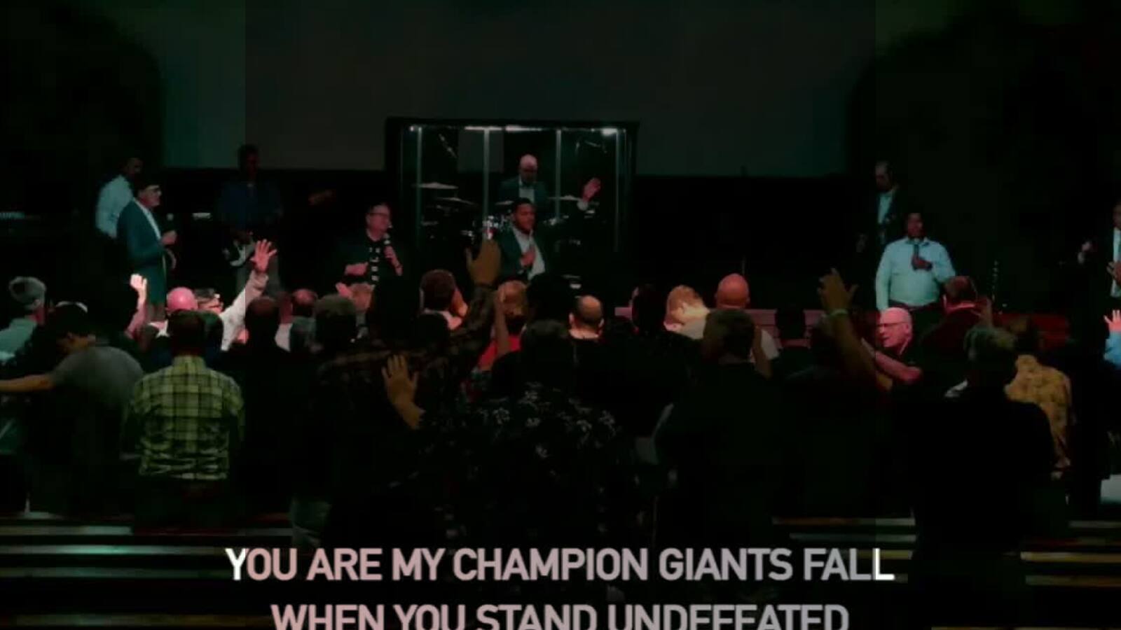 Men in worship at Wisconsin Men's Camp 2025 with projected lyrics visible in the background