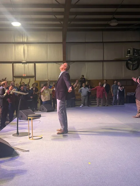 Speaker standing on the open stage as men pray around him.